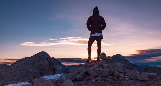 Una persona in cima alla montagna, simbolo del raggiungimento dell'eccellenza attraverso la dedizione e la perseveranza. Le vette più alte si conquistano con passi costanti e determinati.